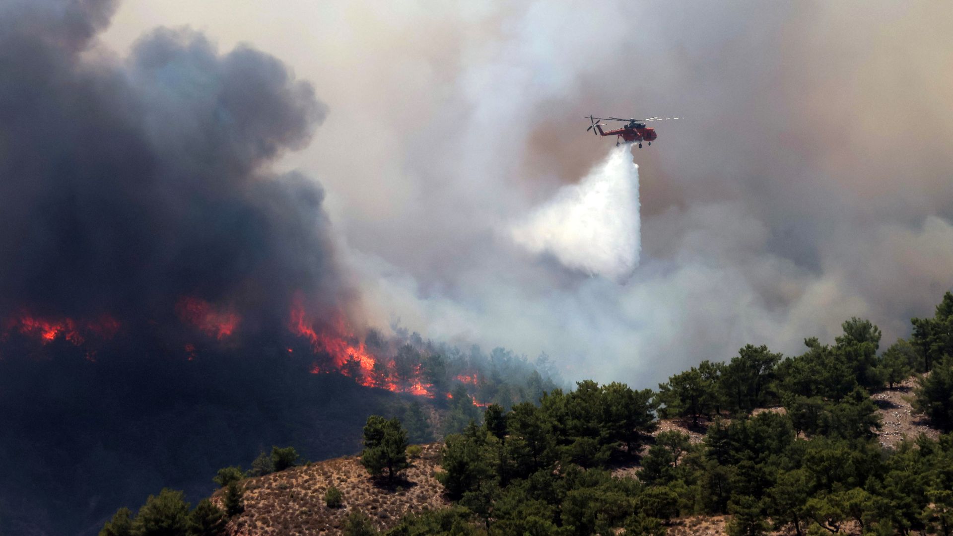 A firefighting helicopter makes a water drop as a wildfire burns near the village of Archangelos, on the island of Rhodes. /Nicolas Economou/Reuters