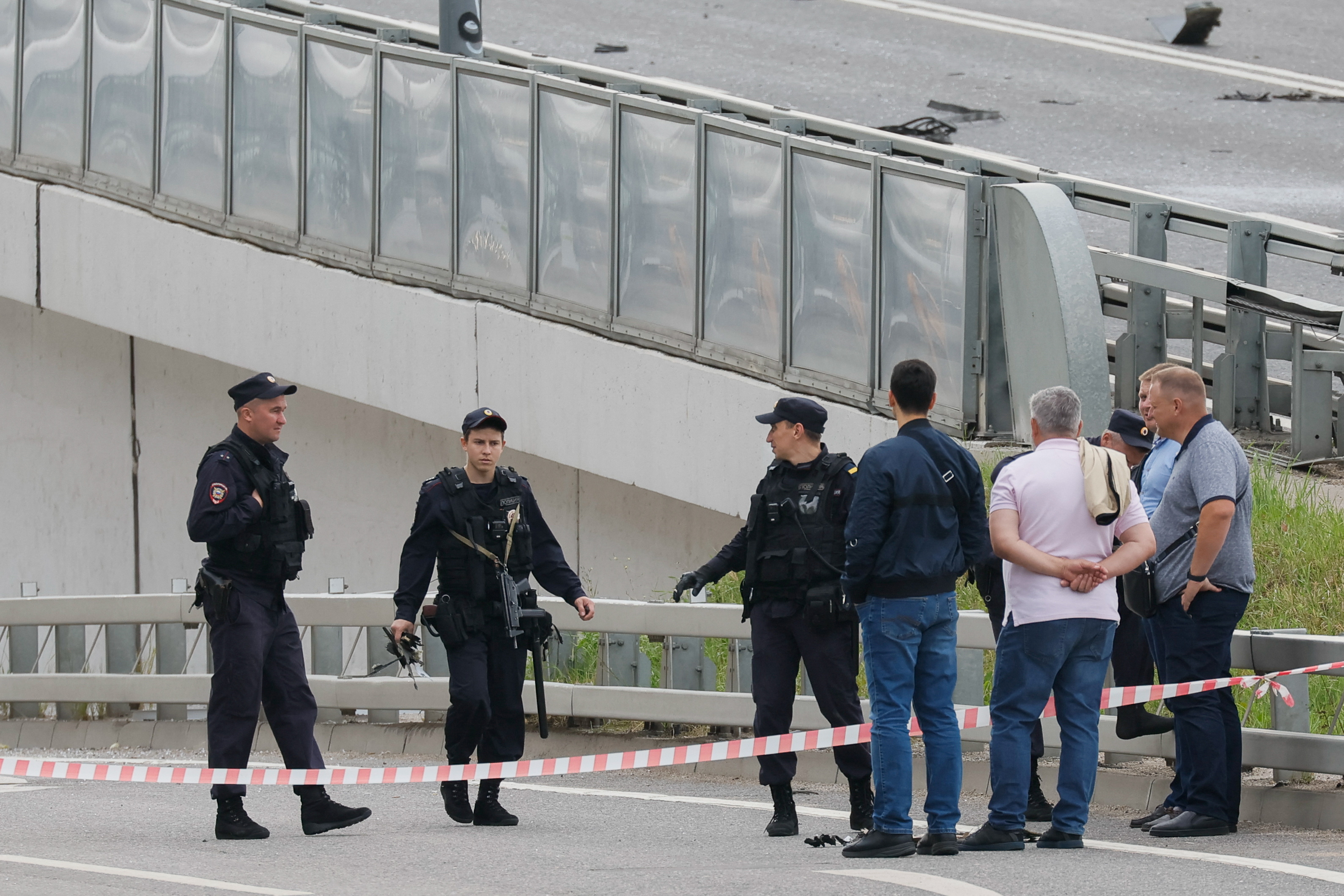 A police officer carries debris to the members of the security services investigating a bridge near the site of a damaged building following a reported drone attack in Moscow. /Reuters/Maxim Shemetov.