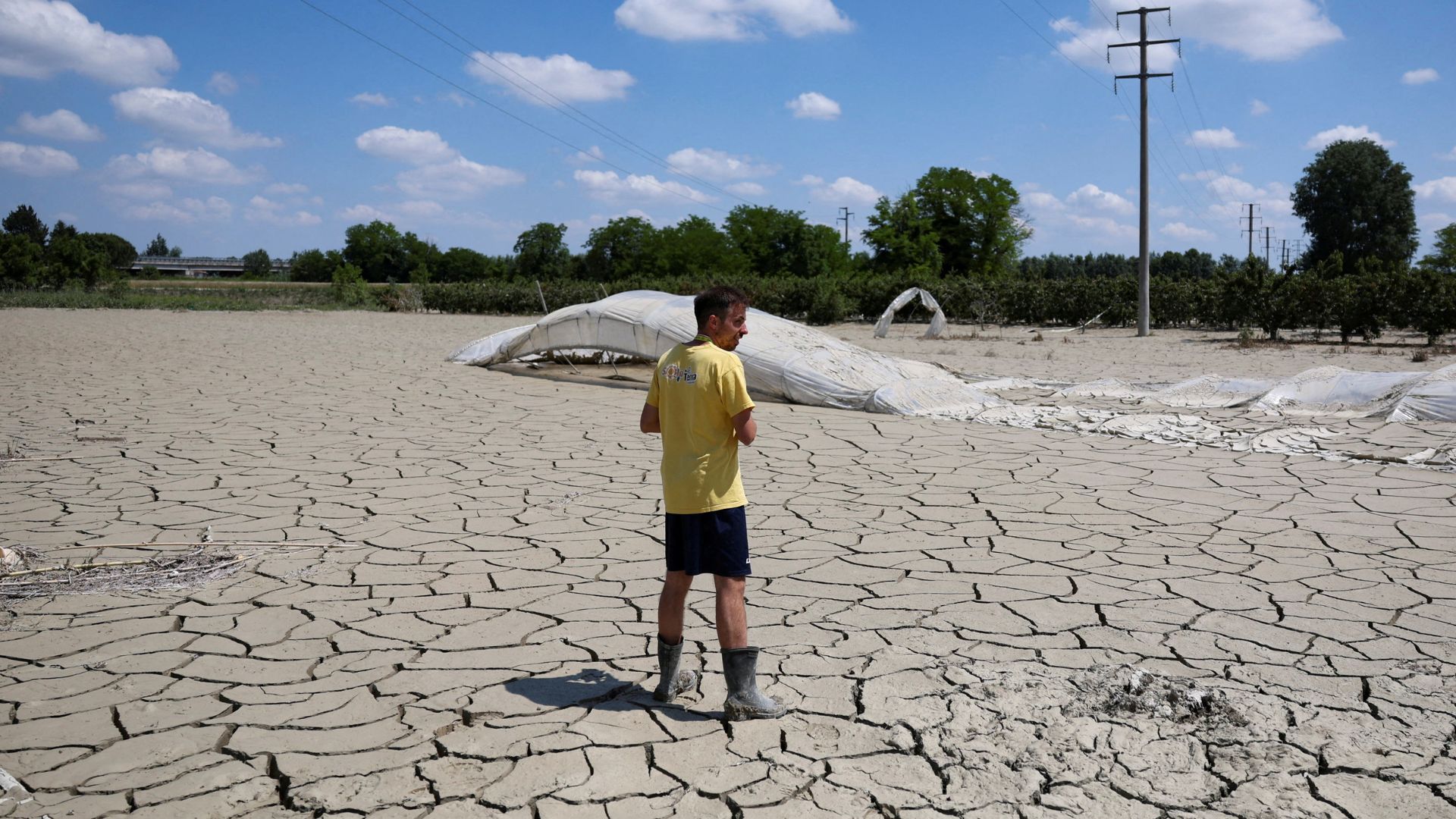  A farmer stands next to a greenhouse in a field covered with cracked solidified mud, in the aftermath of deadly floods in Emilia-Romagna. /Claudia Greco/Reuters