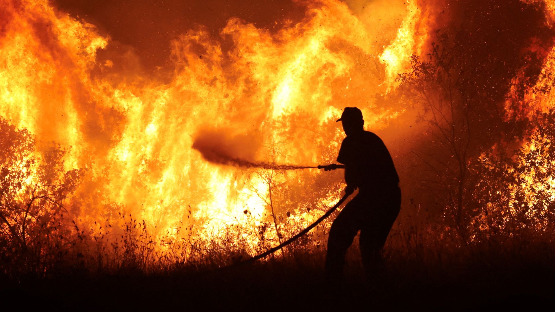 A firefighter tries to extinguish a wildfire burning at the industrial zone of the city of Volos. /Alexandros Avramidis/Reuters 