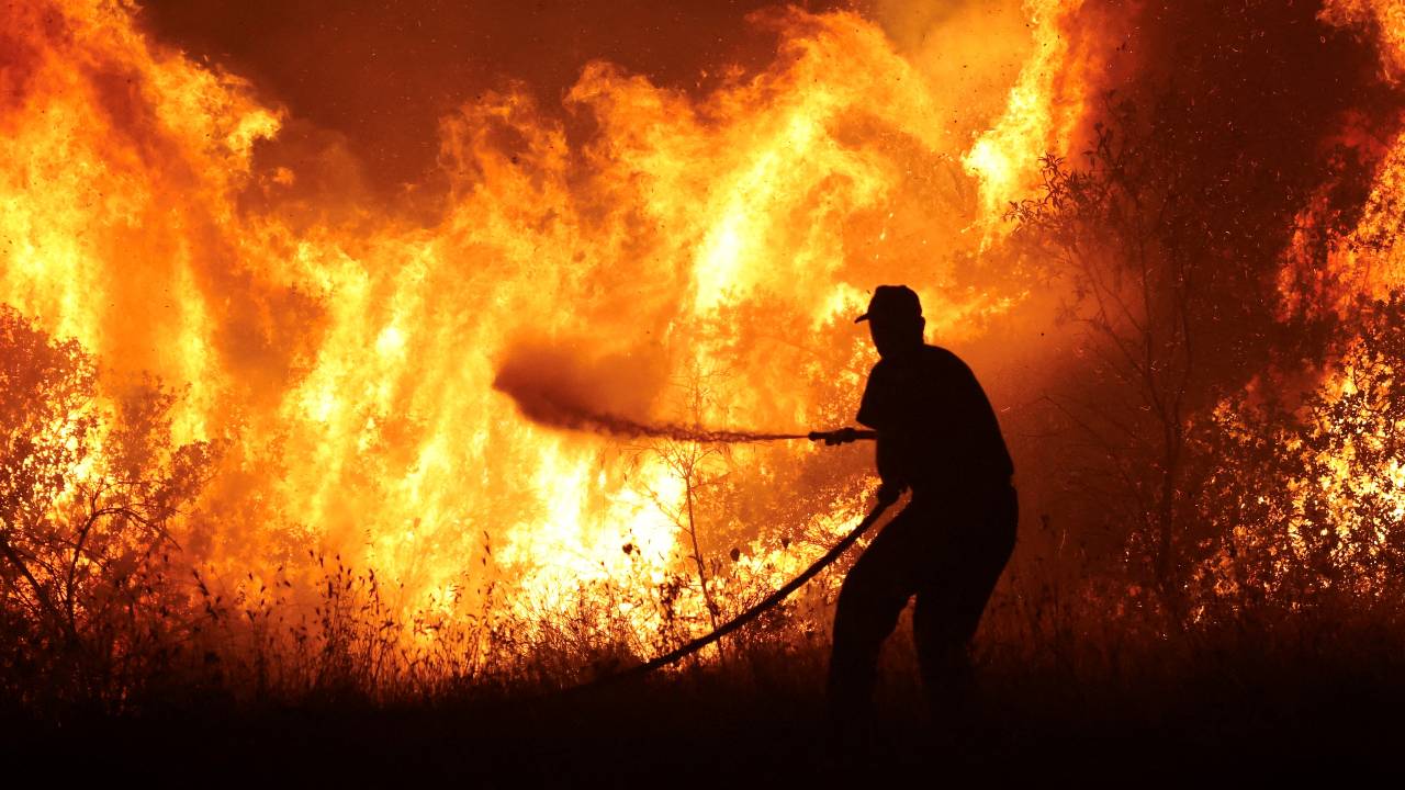 A firefighter tries to extinguish a wildfire burning at the industrial zone of the city of Volos in central Greece. /Alexandros Avramidis/Reuters