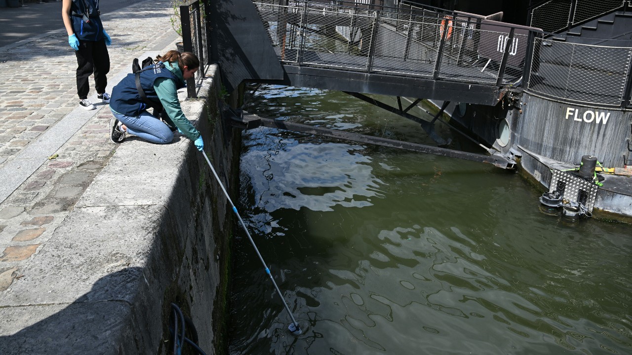 An employee of the company Fluidion collects a sample of water from the Seine to analyze its composition near the Pont Alexandre III in Paris, on August 4, 2023. /Bertrand Guay/AFP