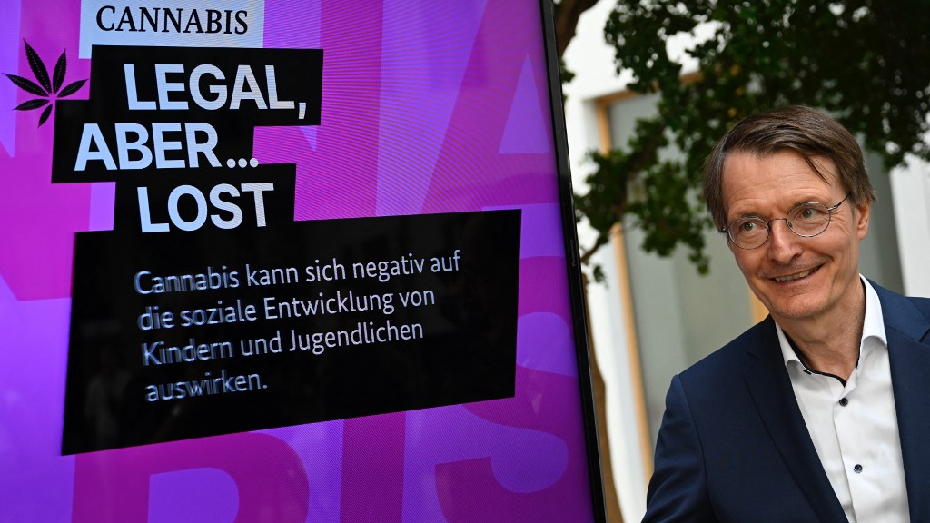 German Health Minister Karl Lauterbach poses next to a campaign poster for legalizing cannabis. /Tobias Schwarz/AFP