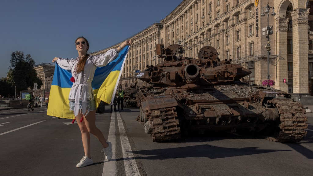 A woman poses holding the Ukrainian flag next to a destroyed Russian armoured vehicle on Ukraine’s Independence Day in Kyiv. /Roman Pilipey / AFP