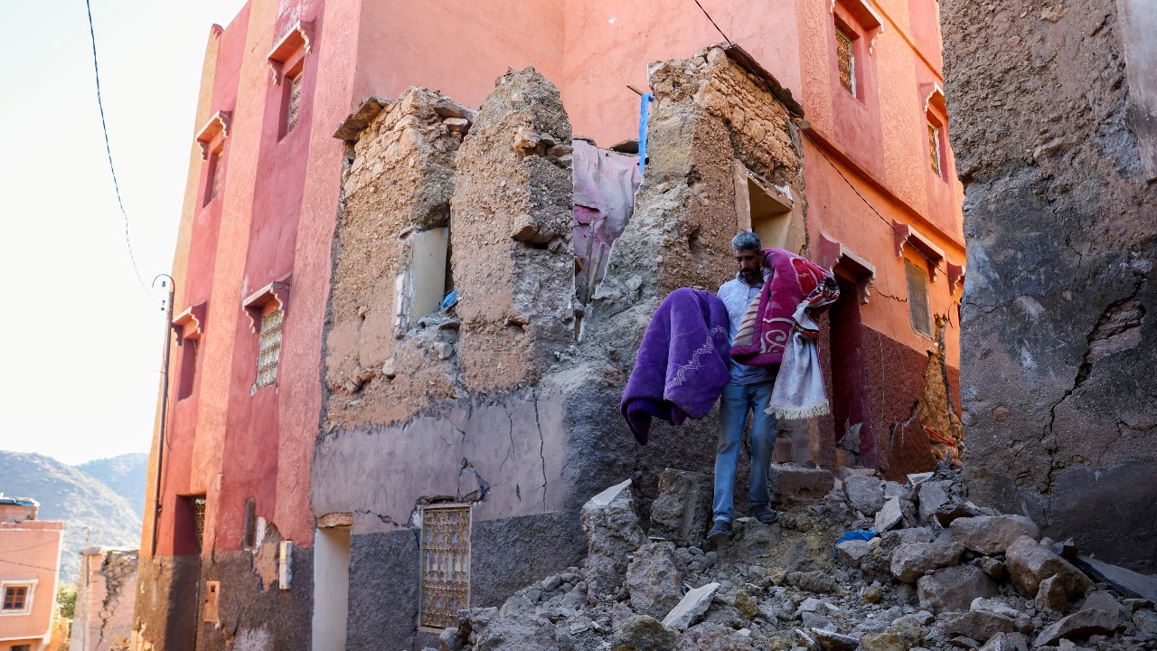 Hussein Adnaie carries belongings out of his damaged house in Moulay Brahim, Morocco. /Hannah McKay/Reuters