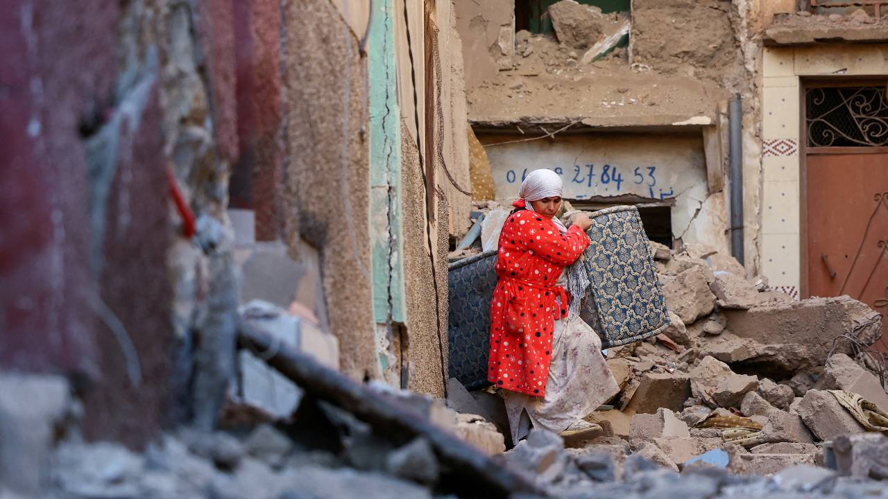 A woman carries belongings out of a damaged building in the aftermath of the deadly quake in Moulay Brahim. /Hannah McKay/Reuters