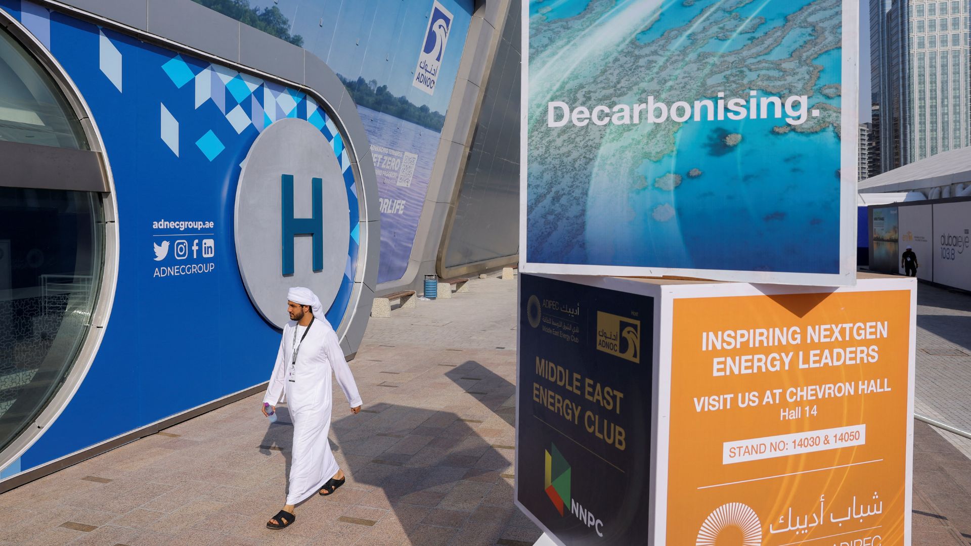 A person walks past a sign that reads 'Decarbonising' at ADIPEC. /Amr Alfiky/Reuters