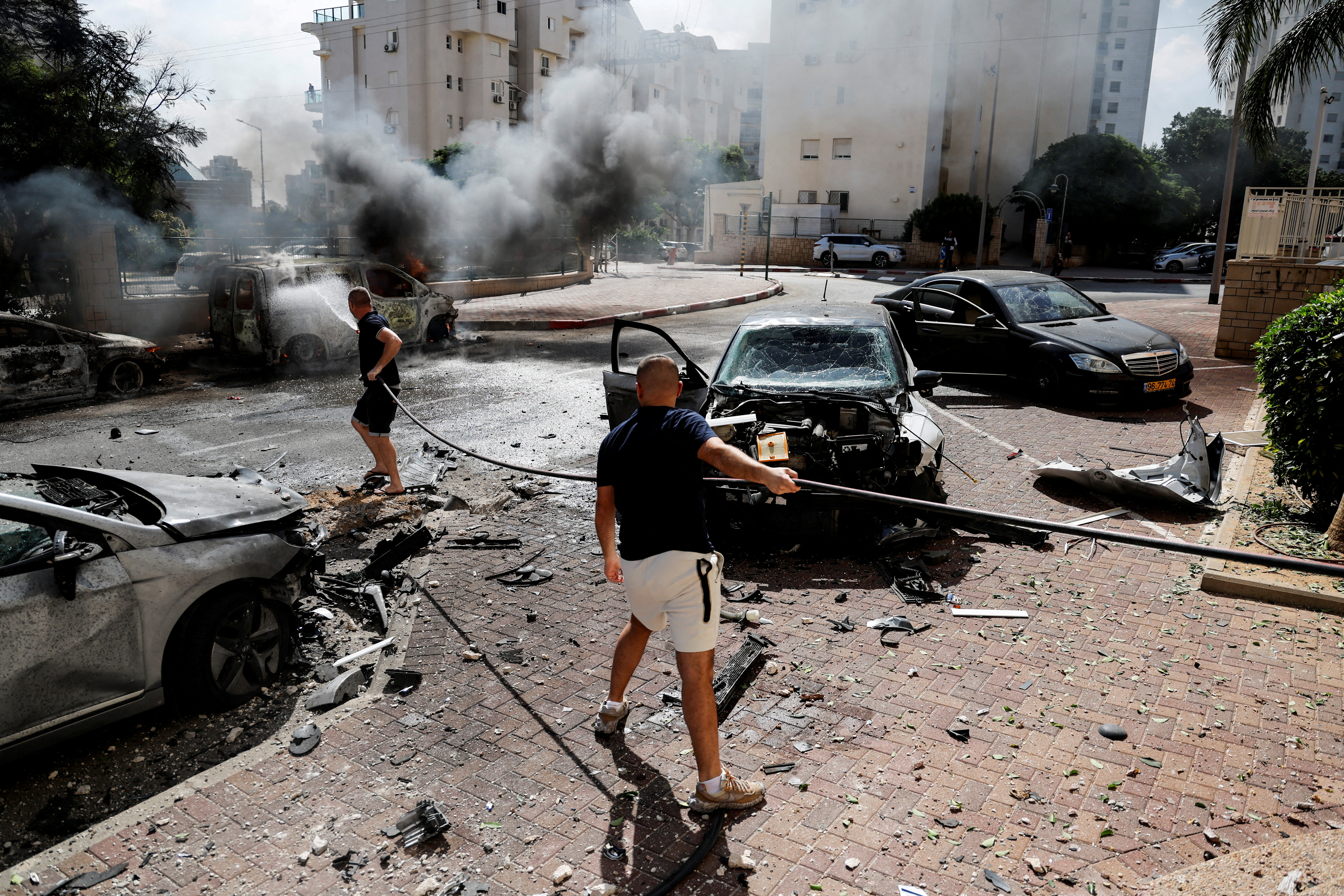 People work to put out a fire engulfing a van, as rockets are launched from the Gaza Strip, in Ashkelon. Ammar Awad/ Reuters 