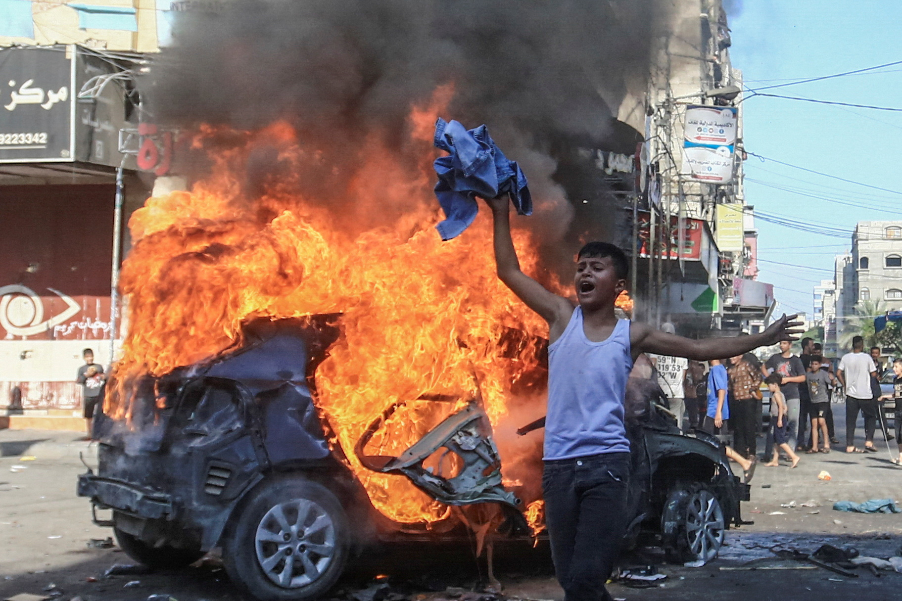 A Palestinian boy reacts next to a burning Israeli vehicle that Palestinian gunmen brought to Gaza after they infiltrated areas of southern Israel. /Mahmoud Issa/Reuters