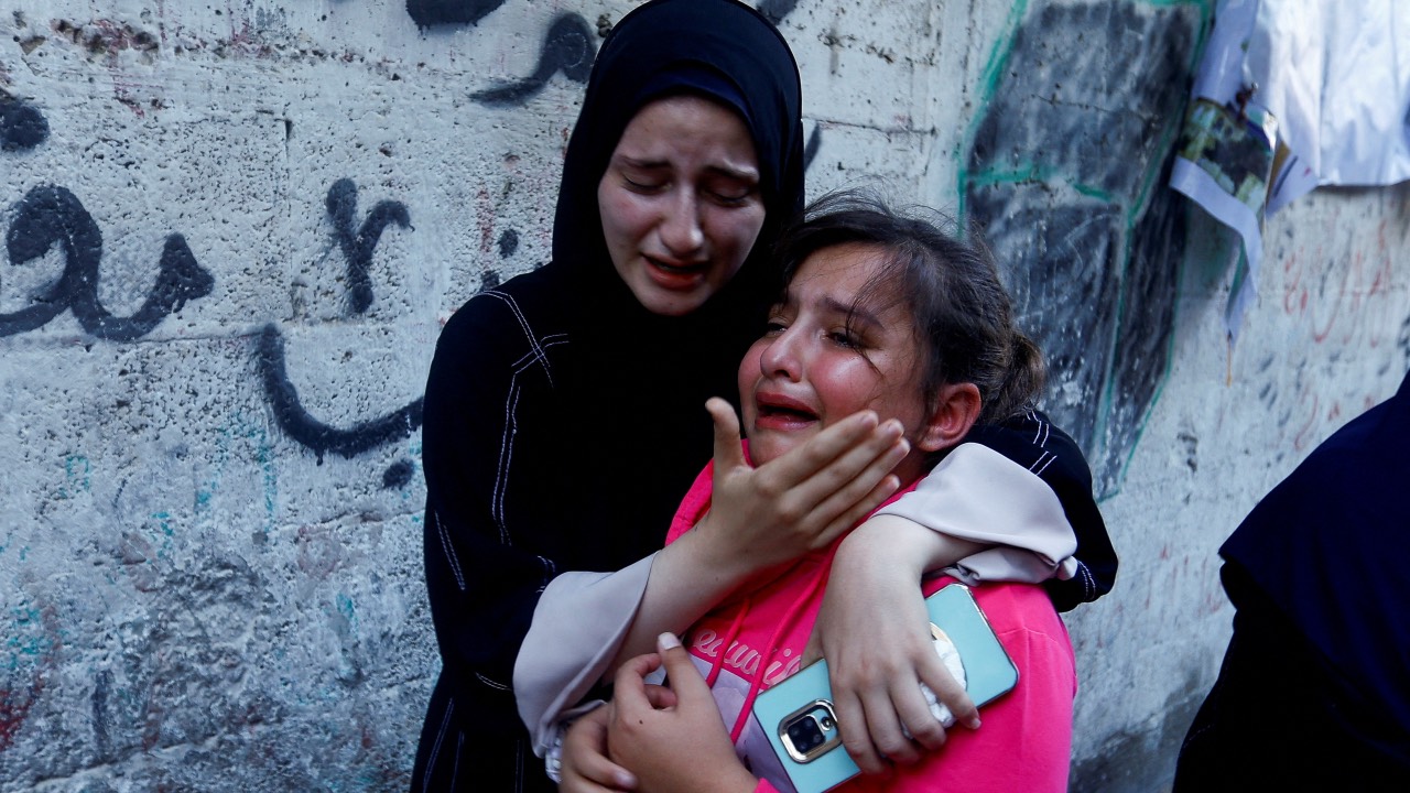 The daughter of Zakaria Abu Maamar, a member of Hamas's political office, is comforted as she cries during her father's funeral, after he was killed in an air strike, in Khan Younis, in southern Gaza Strip. /Ibraheem Abu Mustafa/Reuters