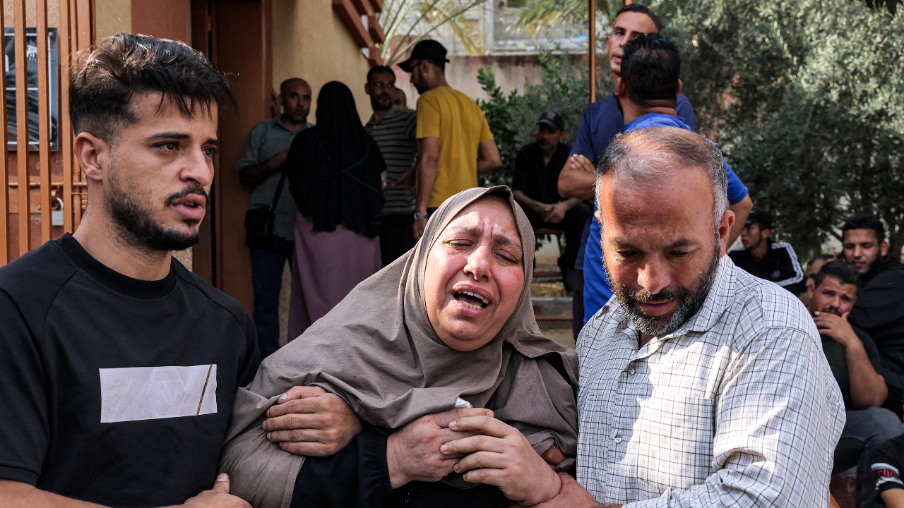 Men console a woman mourning for loved ones killed in an Israeli air strike outside a morgue in Khan Yunis in the southern Gaza Strip. /Said Khatib/AFP