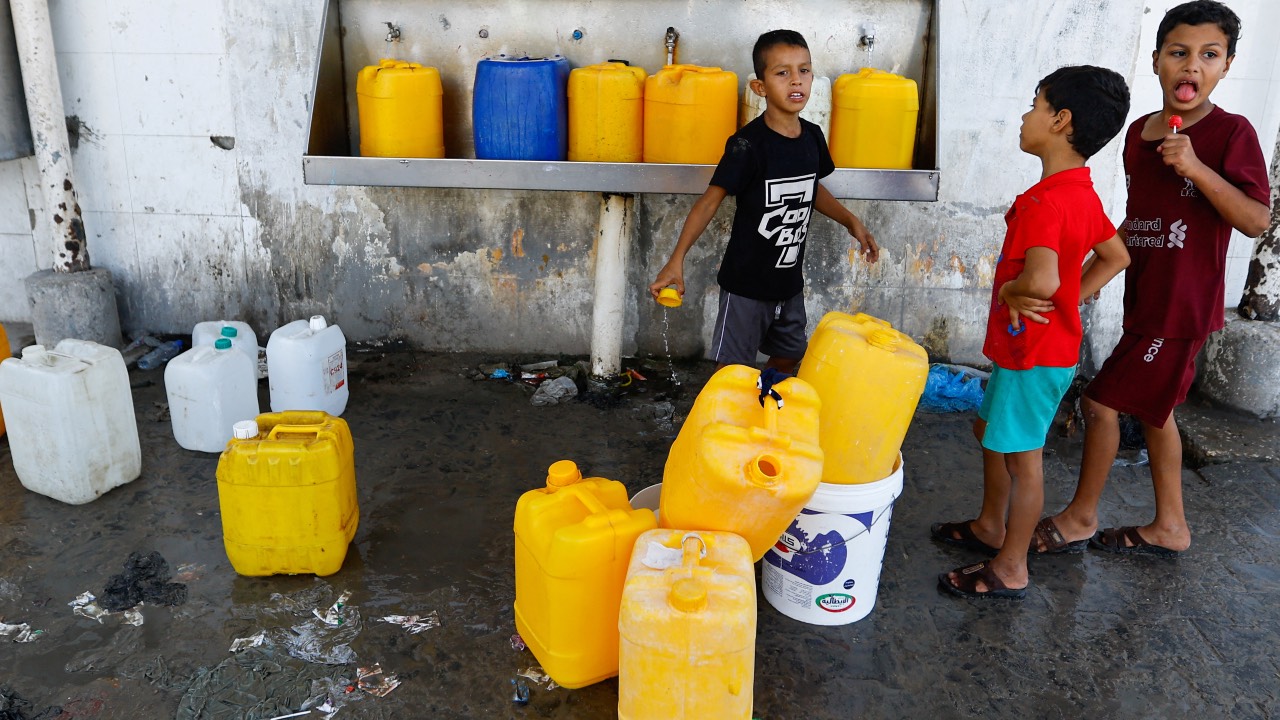 Palestinian children stand as they fill containers with water from public taps amid the conflict with Israel in Khan Younis, in the southern Gaza Strip. /Ibraheem Abu Mustafa/Reuters