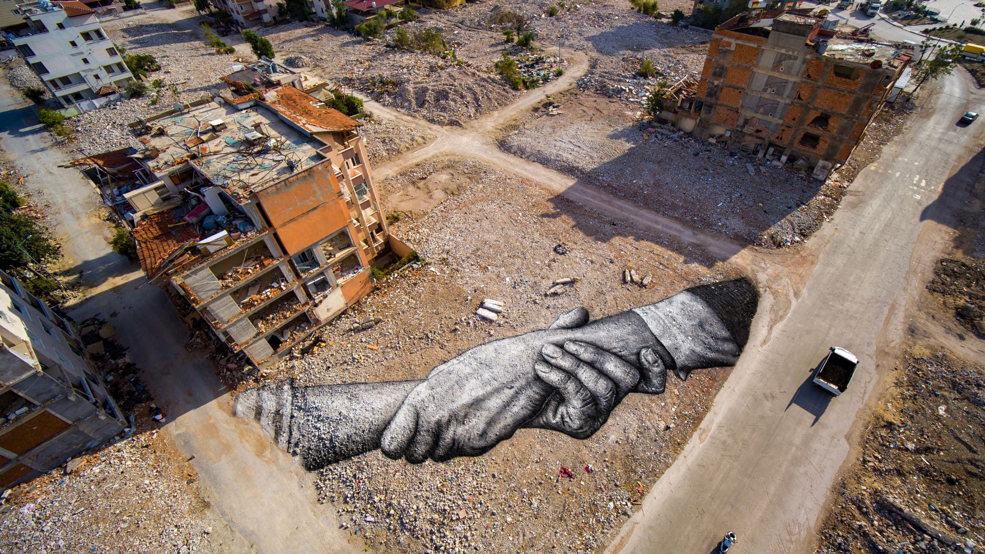 Giant biodegradable landart painting located between damaged buildings by French-Swiss artist Guillaume Legros, known as Saype, from the Beyond Walls project in Hatay. /Handout/LeSabe/AFP