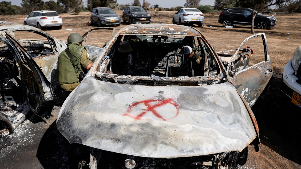 Israeli soldiers inspect the burnt car of a festival-goer at the site of an attack on the Nova Festival by Hamas gunmen, near Israel's border with the Gaza Strip, in southern Israel. /Amir Cohen/Reuters