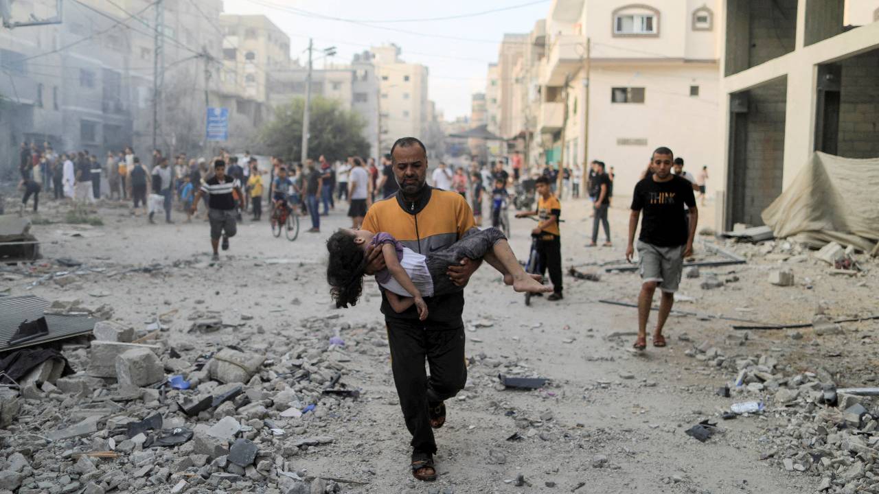 A Palestinian man carries a wounded girl at the site of Israeli strikes in Khan Younis in the southern Gaza Strip. /Yasser Qudih/Reuters