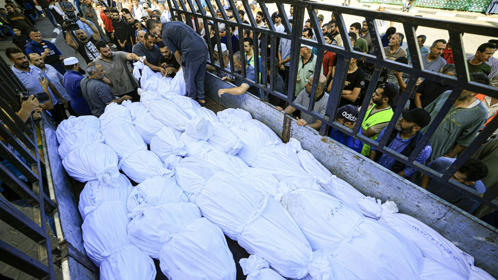 A lorry carries bodies wrapped in burial shrouds of the Abu al-Awf family and other victims, displaced from northern Gaza and killed in a home housing internally displaced Palestinians. /Mahmud Hams/AFP