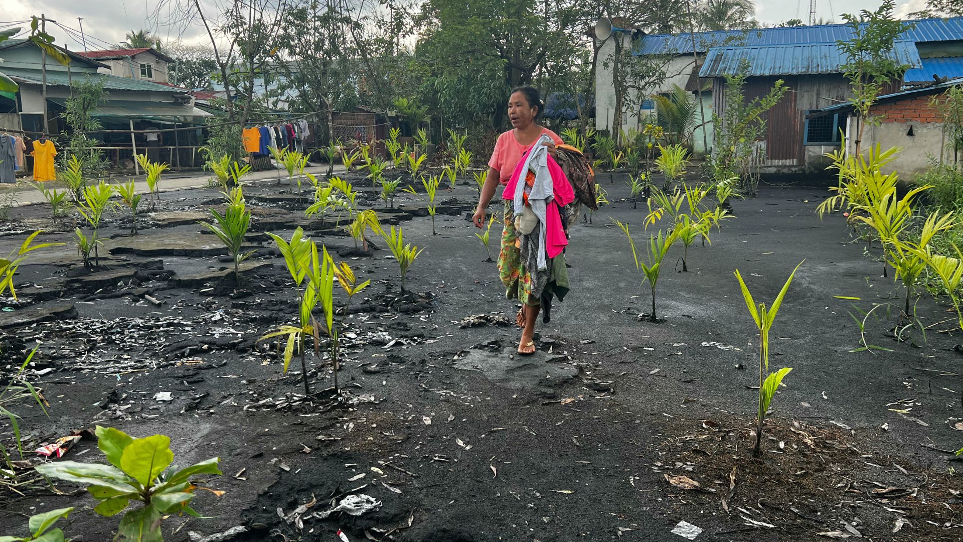 A woman walks over plastic waste covered up with a mixture of chaff and sand in Yangon's Shwepyithar township. /STR/AFP
