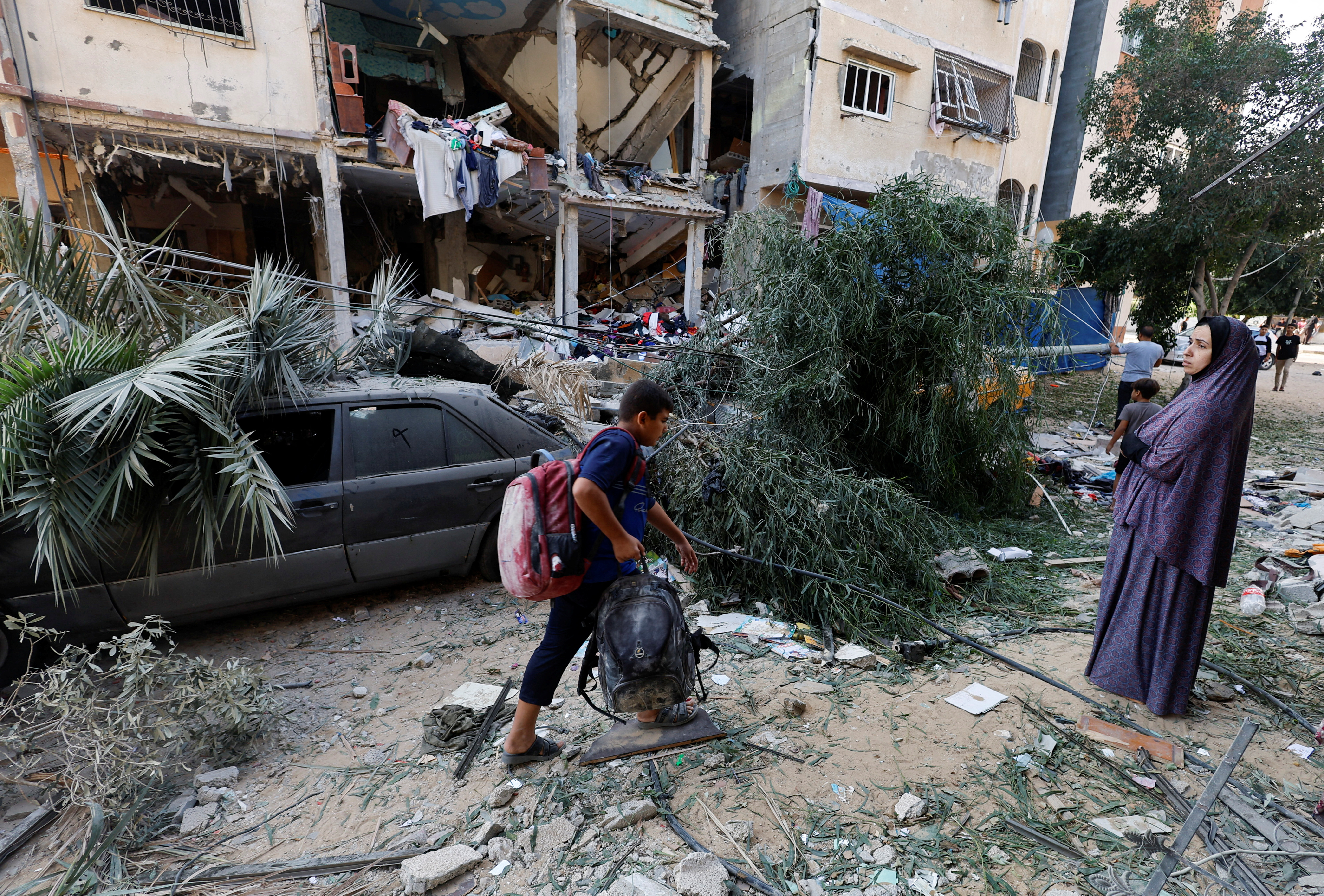 A boy walks with his belongings at the site of Israeli strikes on a house in Khan Younis, southern Gaza. Mohammed Salem. /Reuters