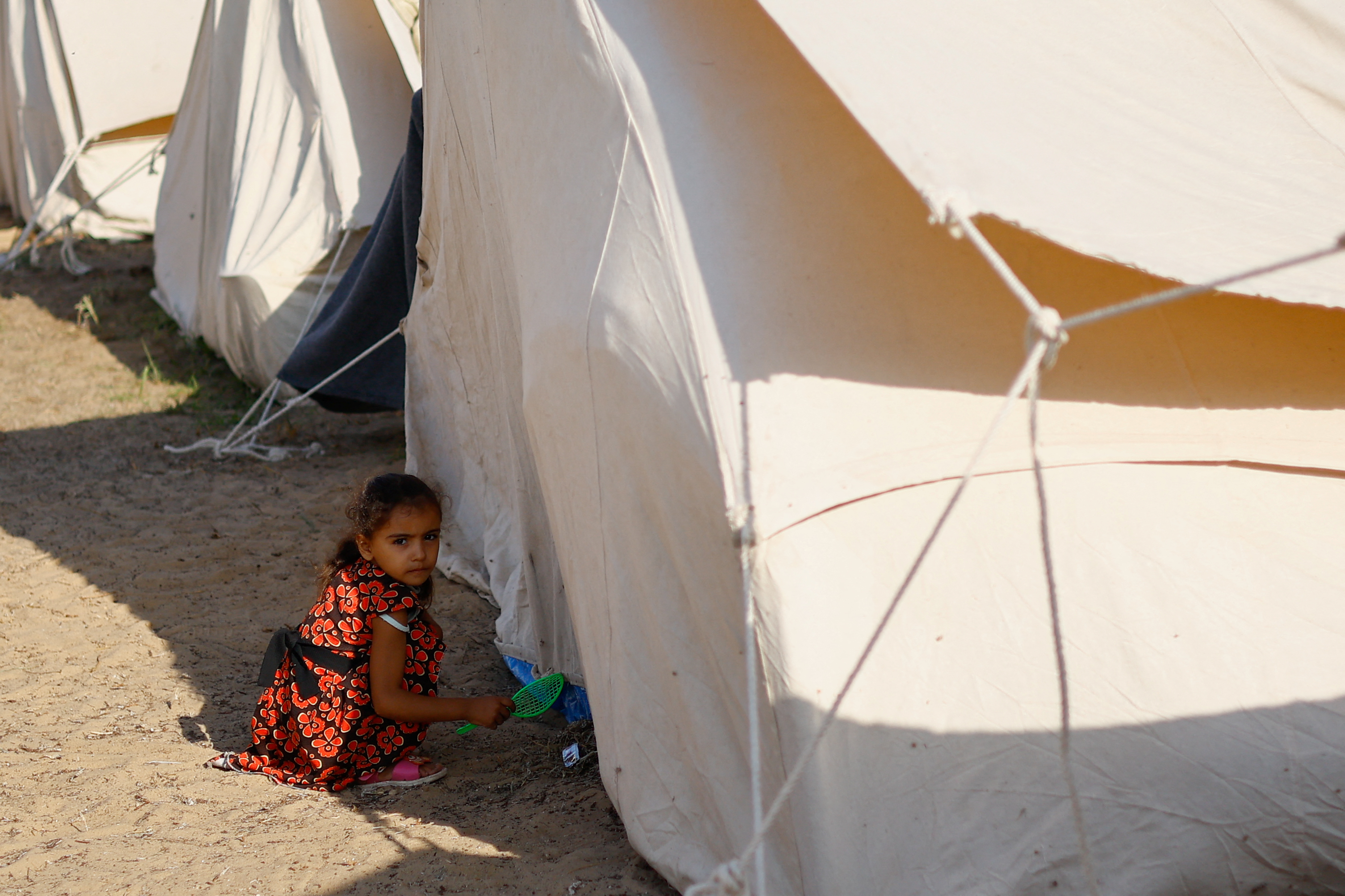 A child outside a tent at a United Nations-run center in Khan Younis. /Ibraheem Abu Mustafa/Reuters