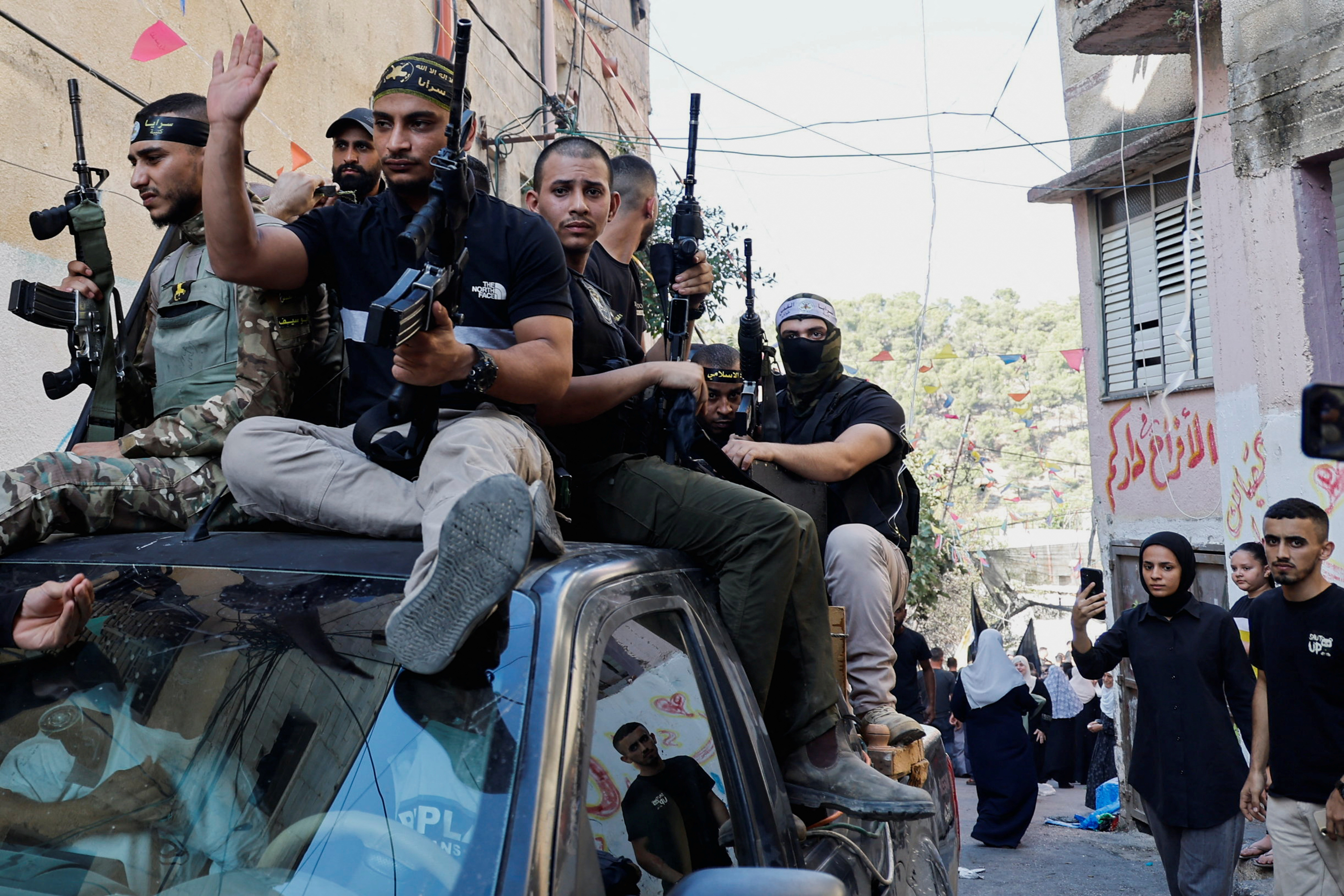 Armed men sit on top of a vehicle during a funeral at Nour Shams camp in Tulkarm in the Israeli-occupied West Bank. /Raneen Sawafta/Reuters