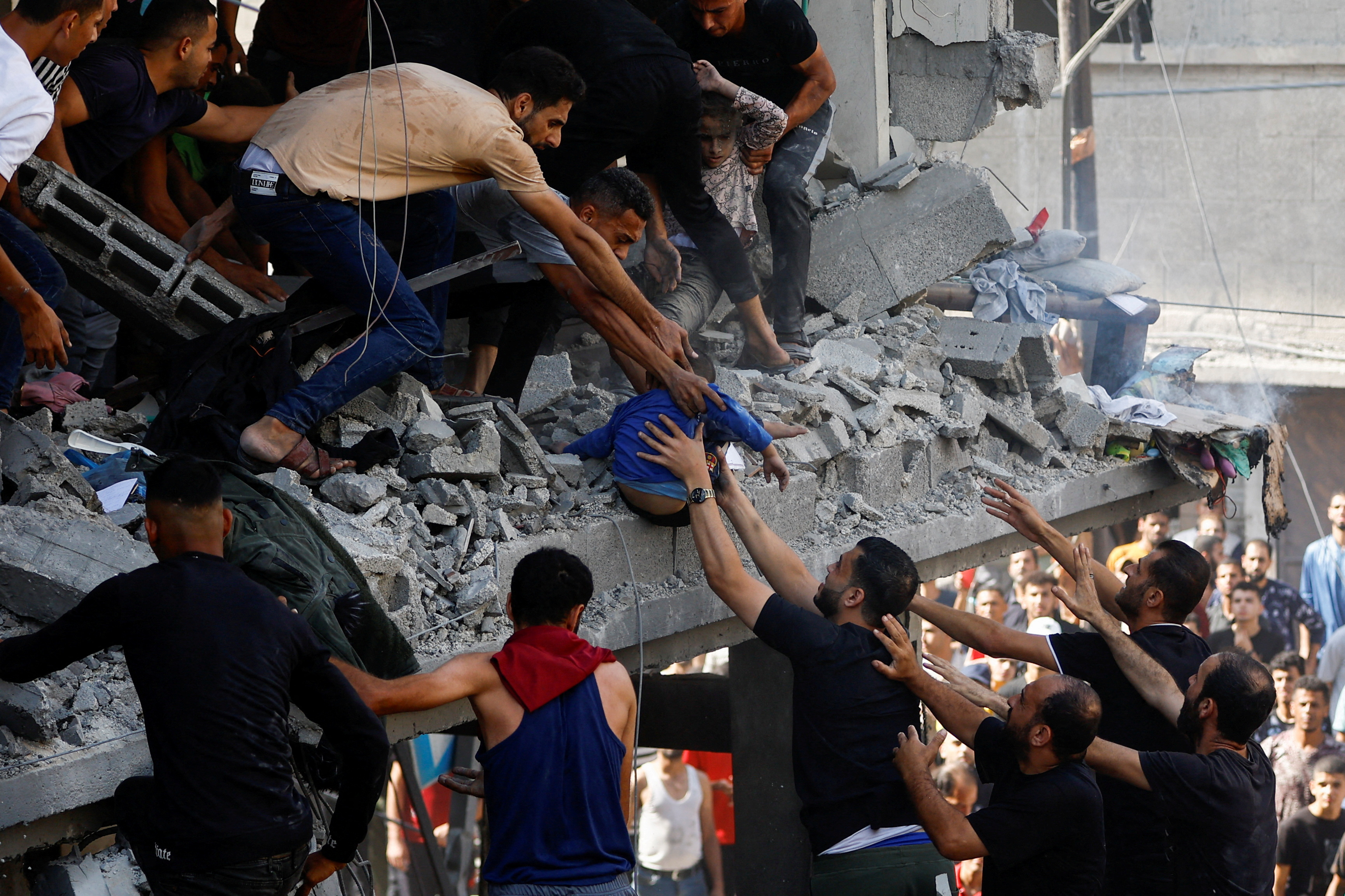 Palestinians carry a child casualty at the site of an Israeli strike on a house, in Khan Younis, in the southern Gaza Strip. /Ibraheem Abu Mustafa