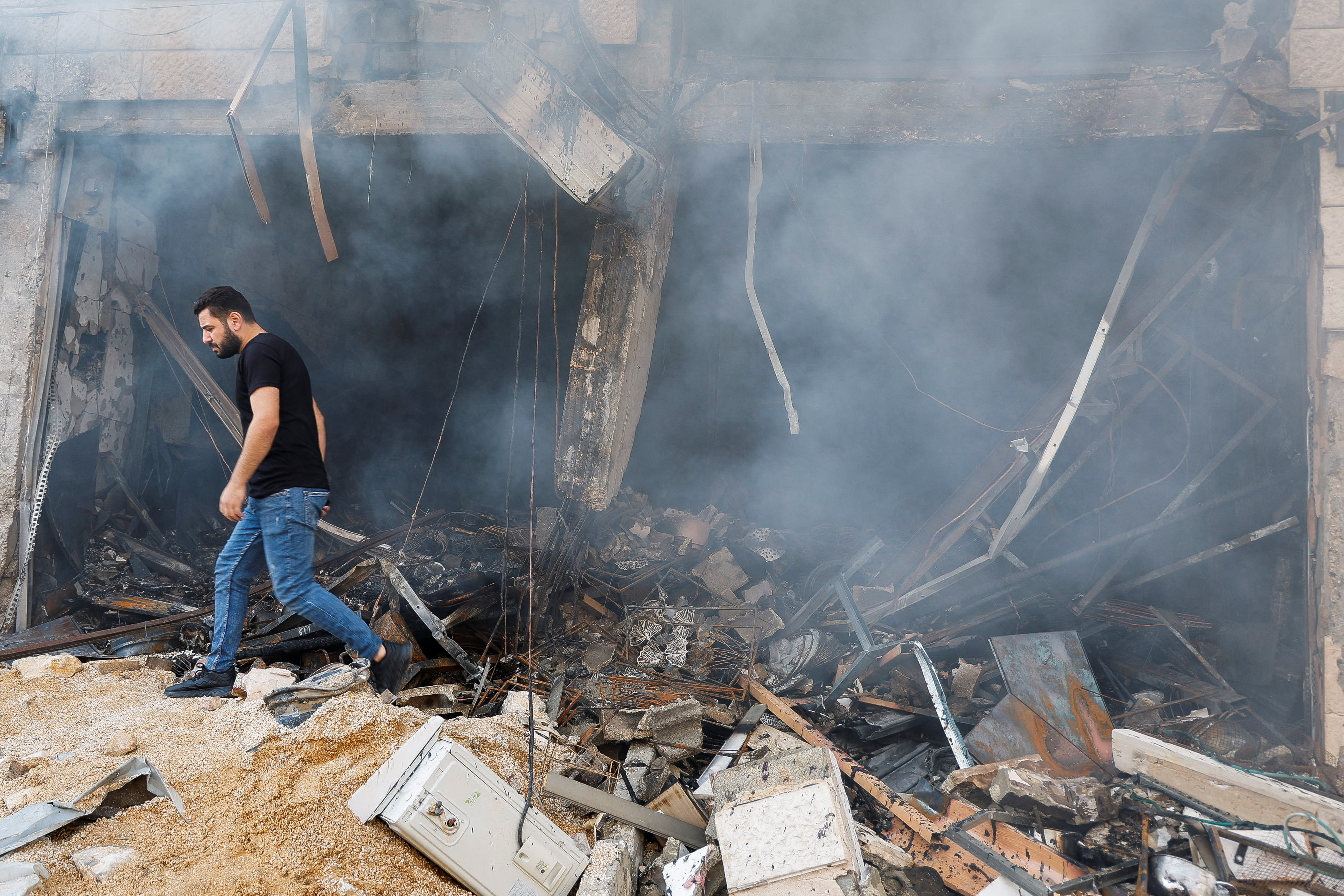 A Palestinian man inspects the wreckage of a house in Gaza after another strike by Israeli forces. /Raneen Sawafta/Reuters