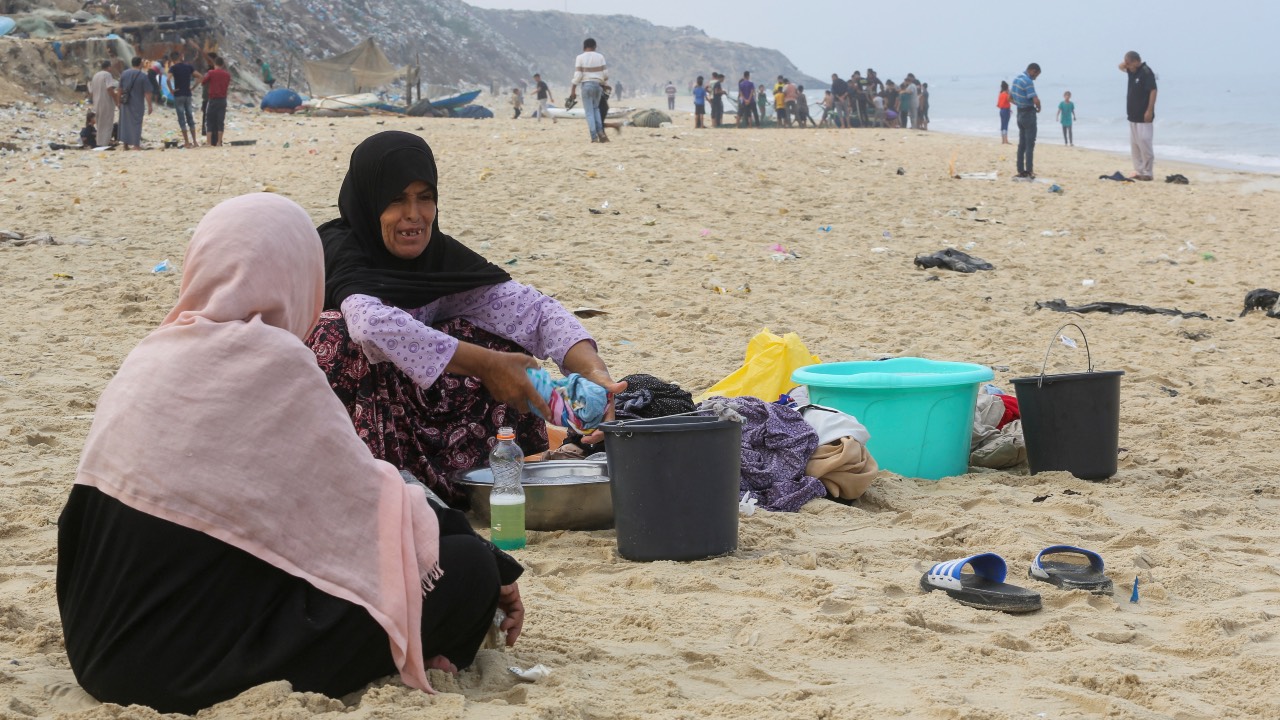 Palestinians wash clothes with seawater, amid a lack of of clean water, on a beach in Deir al-Balah, in the central Gaza Strip. /Ahmed Zakot/Reuters