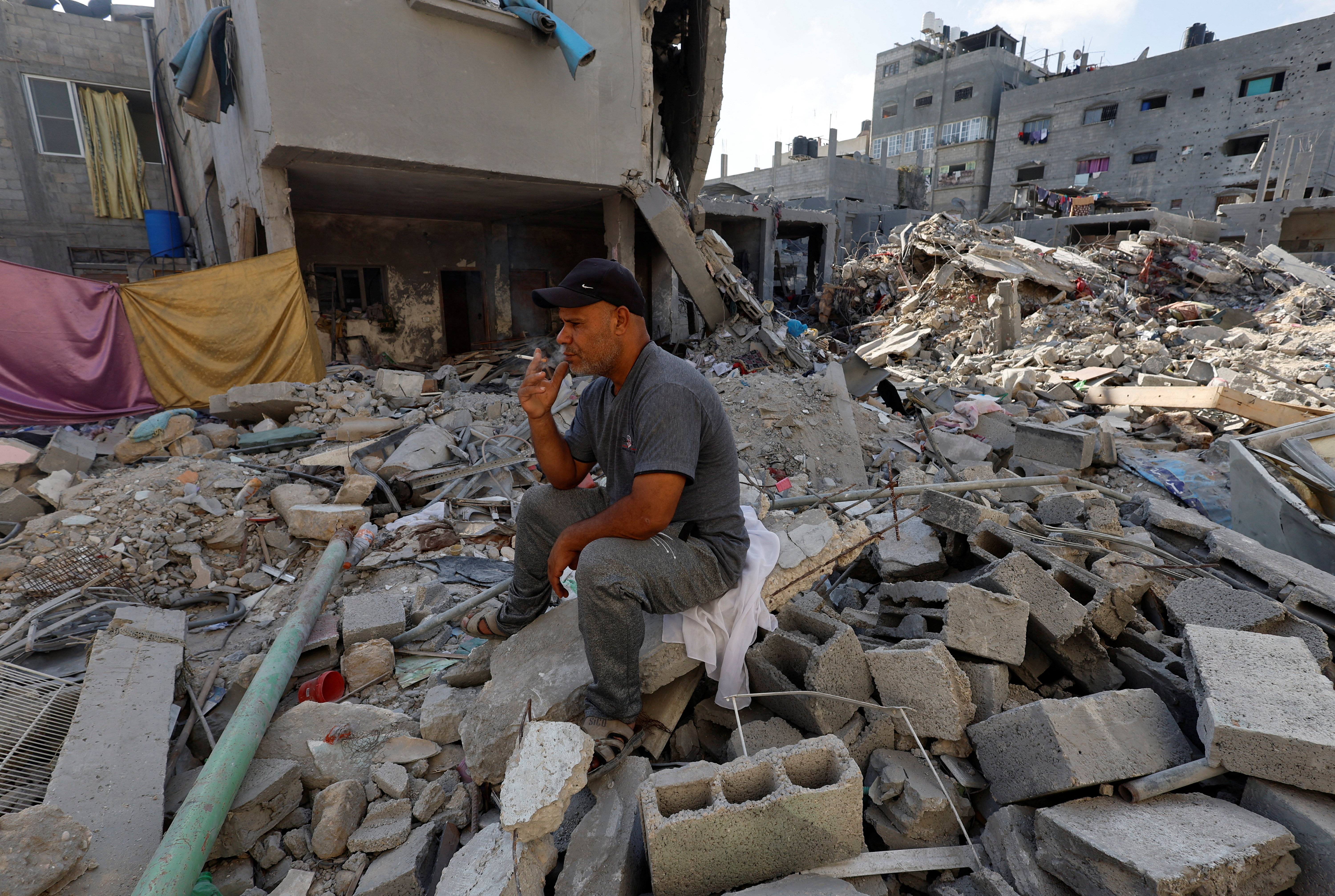 A Palestinian man sits among the debris of his home that was destroyed by an Israeli strike in Khan Younis in the southern Gaza. /Mohammed Salem/Reuters
