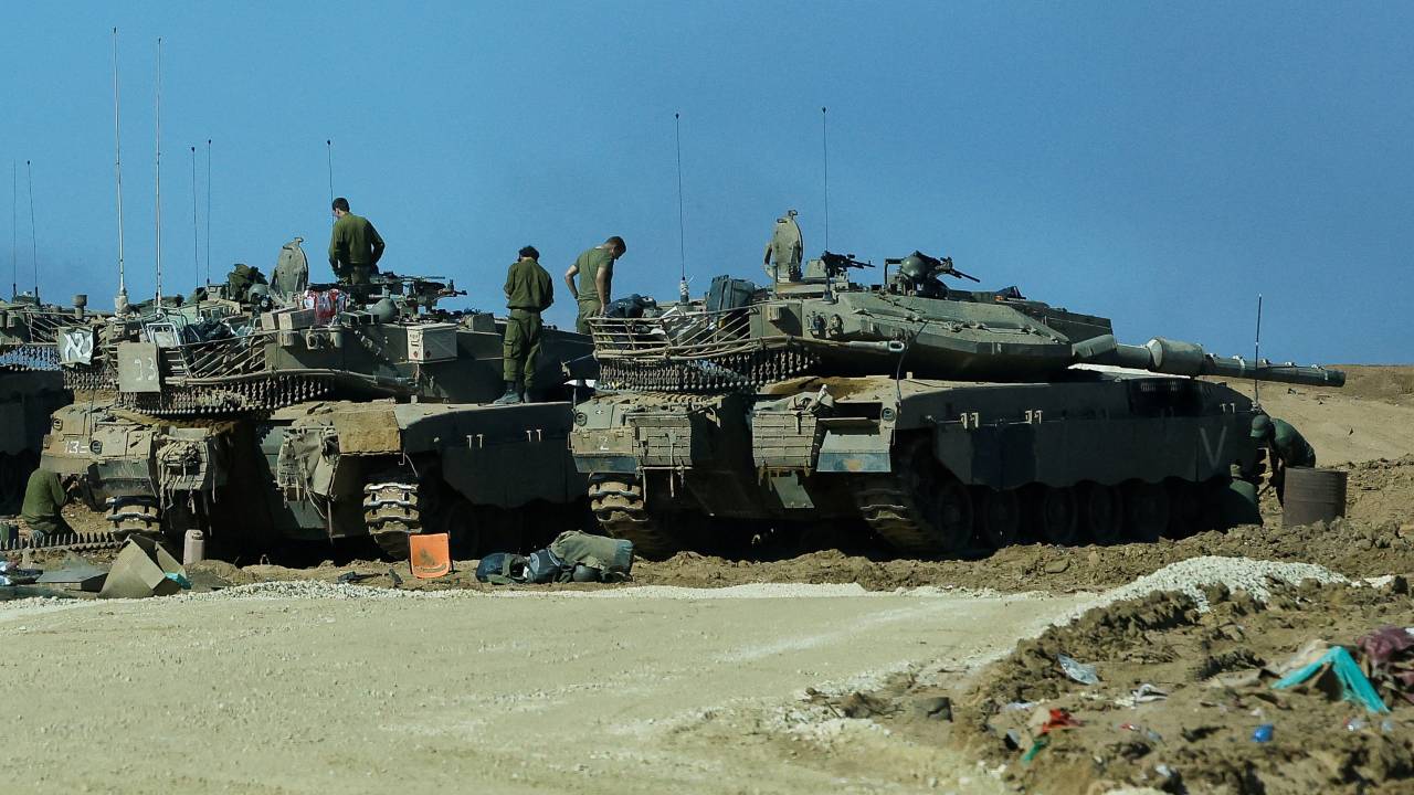 Members of the Israeli military walk on tanks near Gaza. /Alexander Ermochenko/Reuters