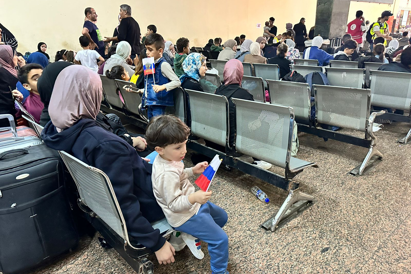 Foreign nationals wait for their papers to be processed on the Egyptian side of the Rafah crossing after fleeing the Gaza Strip. /AFP