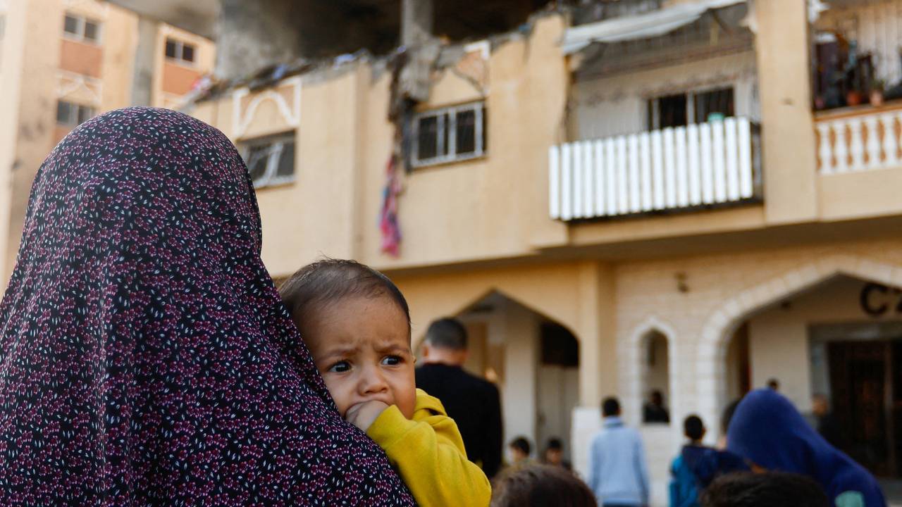 A woman holding a baby stands at the site of an Israeli strike on the apartment building in Khan Younis in the south Gaza. /Ibraheem Abu Mustafa /Reuters