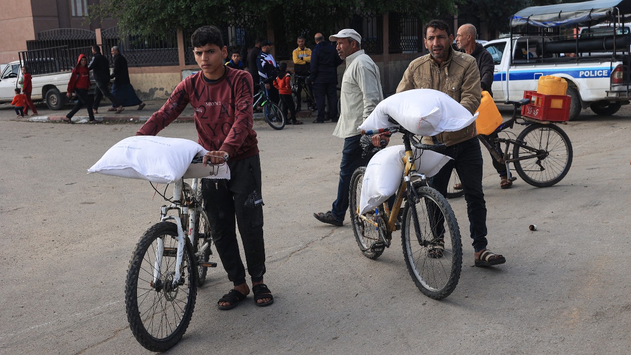 Palestinians receive bags of flour from the United Nations Relief and Works Agency for Palestine Refugees (UNRWA). /Said Khatib/AFP