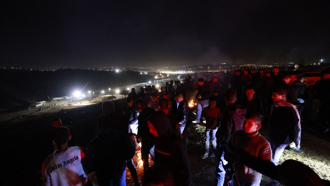 People gather on a hill overlooking the Israeli Ofer military facility in Baytunia in the occupied West Bank as they wait for the release of Palestinian prisoners in exchange for Israeli hostages freed by Hamas. /Jaafar Ashtiyeh/AFP