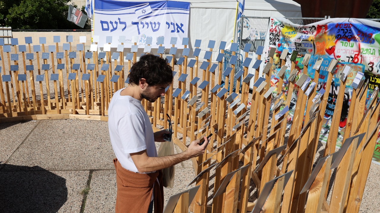 A man takes a picture of an installation set up in Tel Aviv for people taken hostage by Hama, hours after the start of a four-day truce in battles between Israel and Hamas. /Jack Guez/AFP