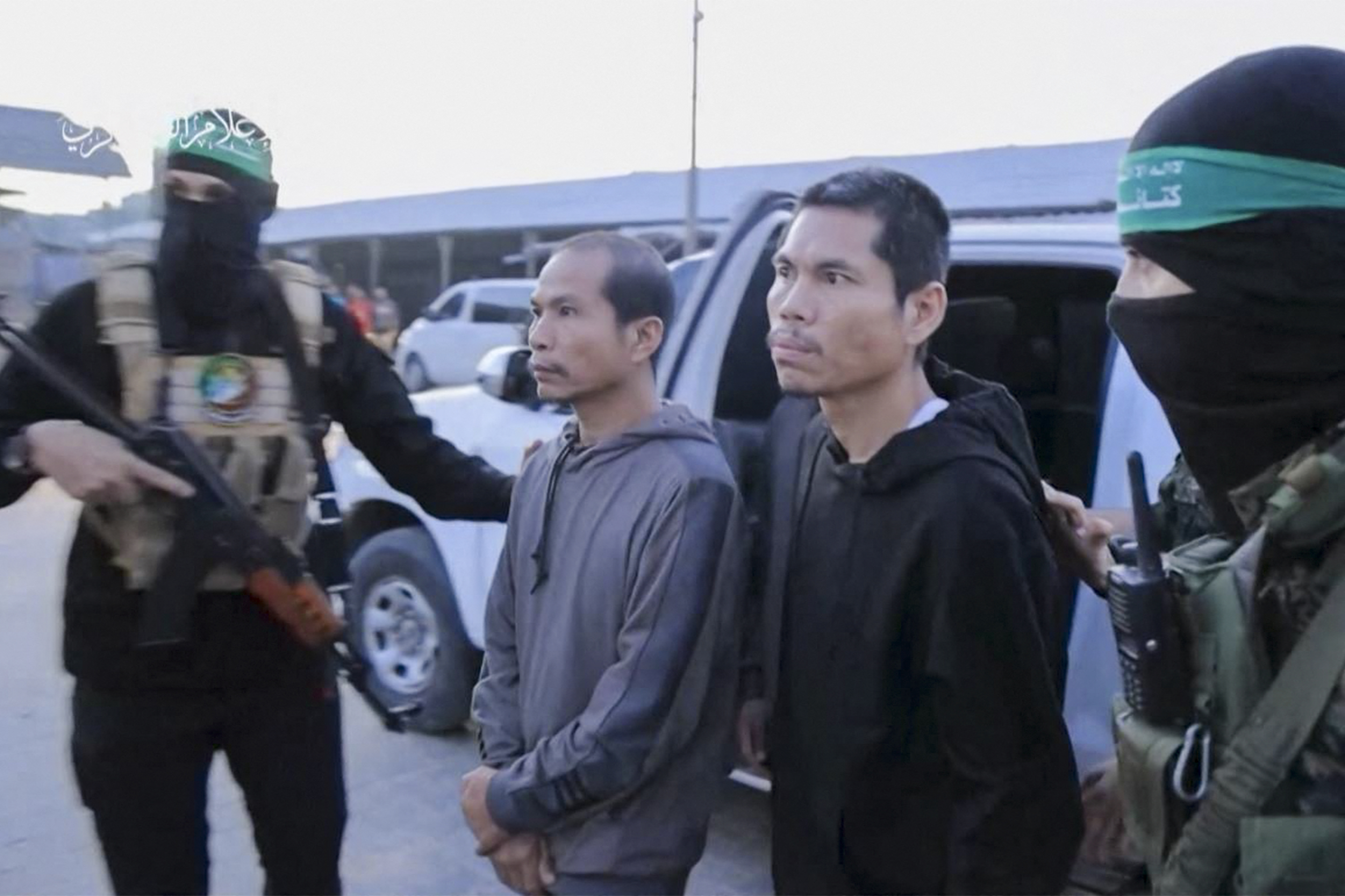 Al-Qassam Brigades lead hostages over to officials from the International Committee of the Red Cross in Gaza on Friday. /Hamas Media Office/AFP