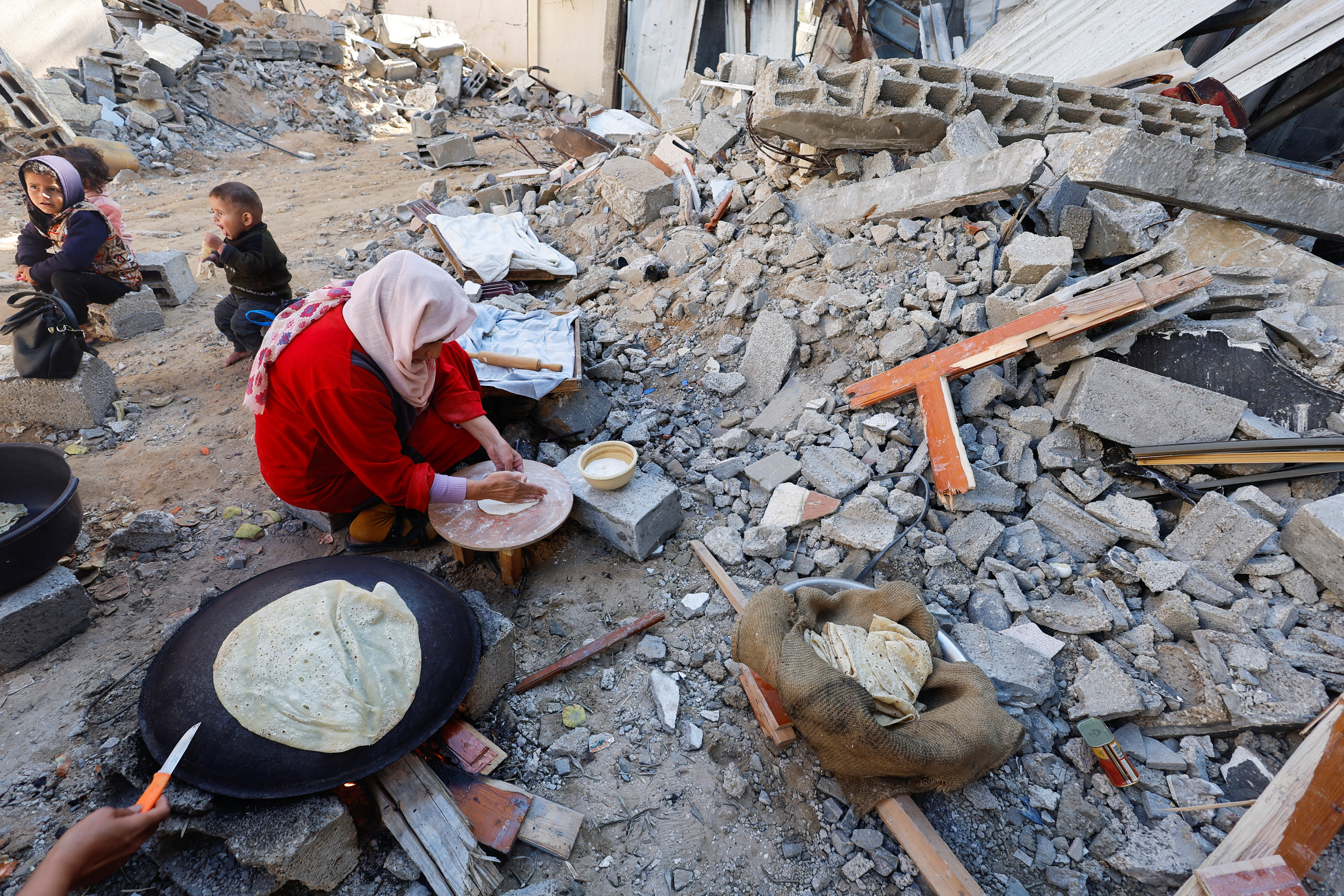 Israel and Hamas struck a last-minute deal to extend their ceasefire for a seventh day. Here, Palestinians make the most of the break in the conflict to bake bread amid the ruins of a missile strike in Gaza. /Mohammed Salem/Reuters