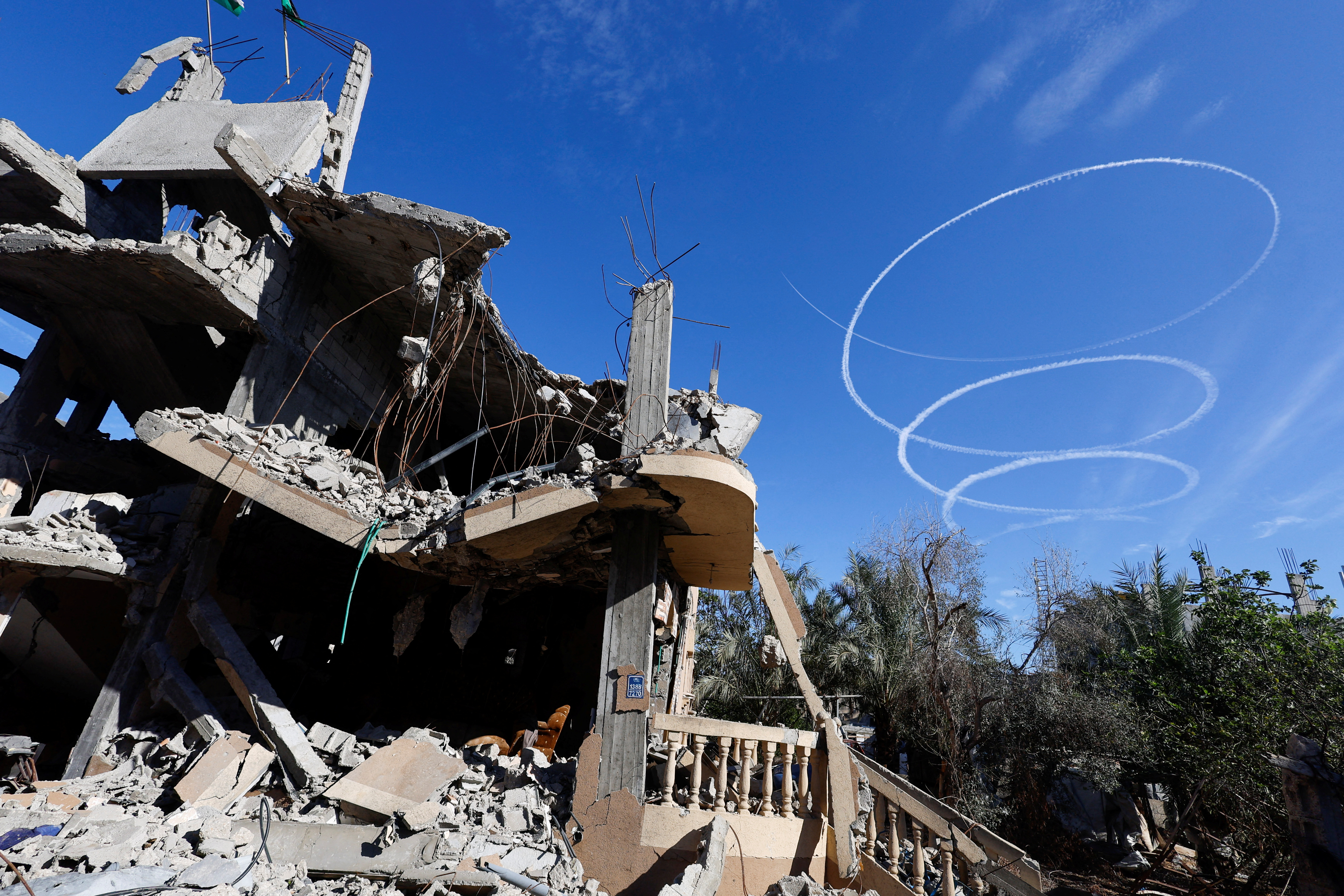Israel aircrafts leave trails near the ruins of houses destroyed during the conflict in Khan Younis, Gaza. /Mohammed Salem/Reuters
