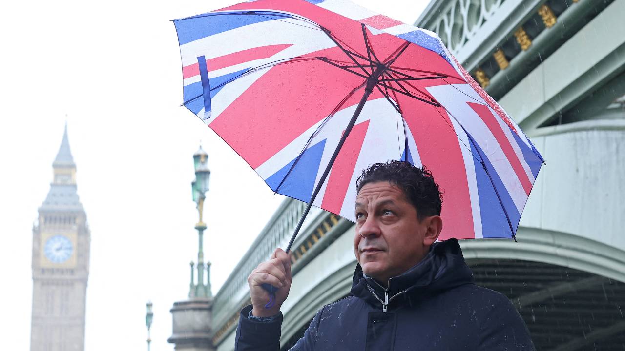 Italian chef-turned restaurant owner Francesco Mazzei shields from the rain in London, his adopted home. He's one of many chefs to have fled west in search of better opportunities. /Toby Melville/Reuters