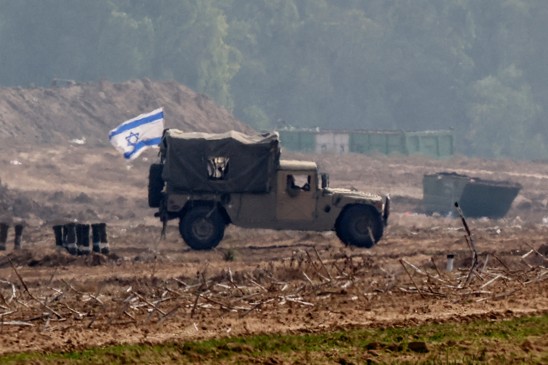 An Israeli flag flies on a military vehicle as the Israeli army operates at the border with Gaza, as seen from southern Israel. /Athit Perawongmetha/Reuters