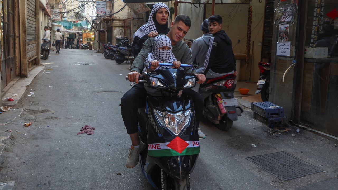 People wearing keffiyehs ride on a motorbike during a global call for strike in solidarity with Gaza and Palestinian people, at Burj al-Barajneh refugee camp in Beirut, Lebanon. /Mohamed Azakir/Reuters
