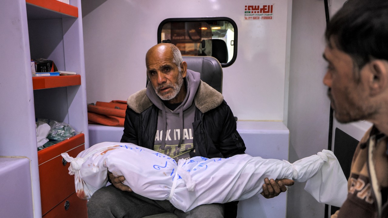 The grandfather of Sidal Abu Jamea, a Palestinian girl from Khan Yunis, carries her wrapped body after she died following Israeli bombardment in Rafah in the southern Gaza Strip. /Mahmud Hams/AFP