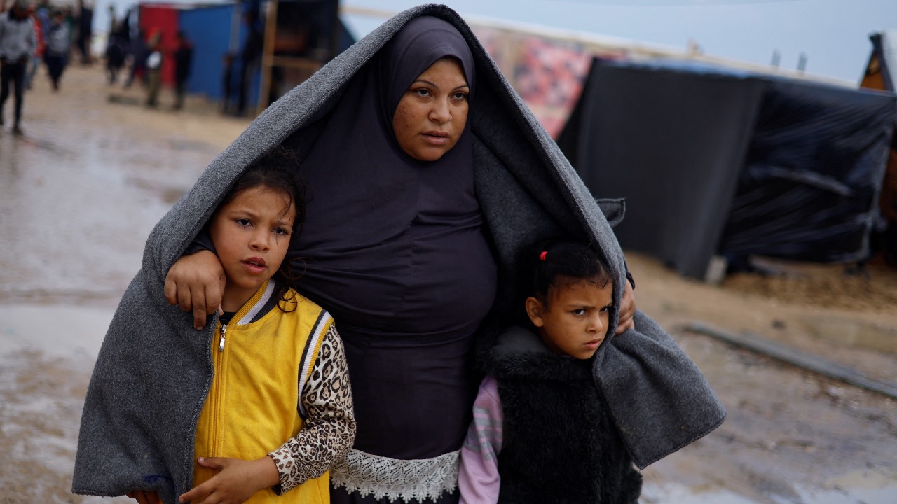 Displaced Palestinians, who fled their houses due to Israeli strikes, walk following heavy rains at tent camps in Rafah, in the southern Gaza Strip. /Mohammed Salem/Reuters