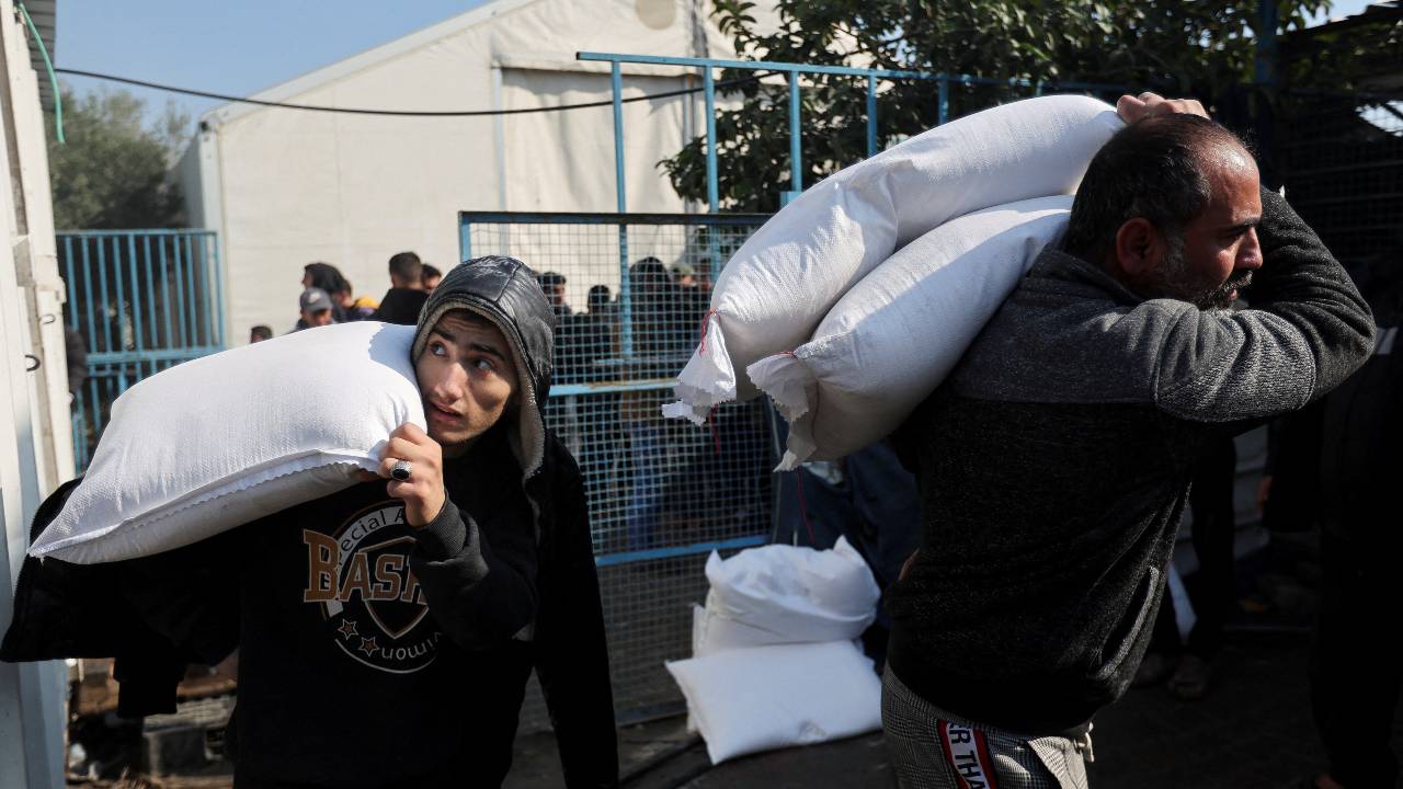 Palestinians carry flour bags distributed by the United Nations Relief and Works Agency during a temporary truce between Hamas and Israel last month. /Ibraheem Abu Mustafa/Reuters