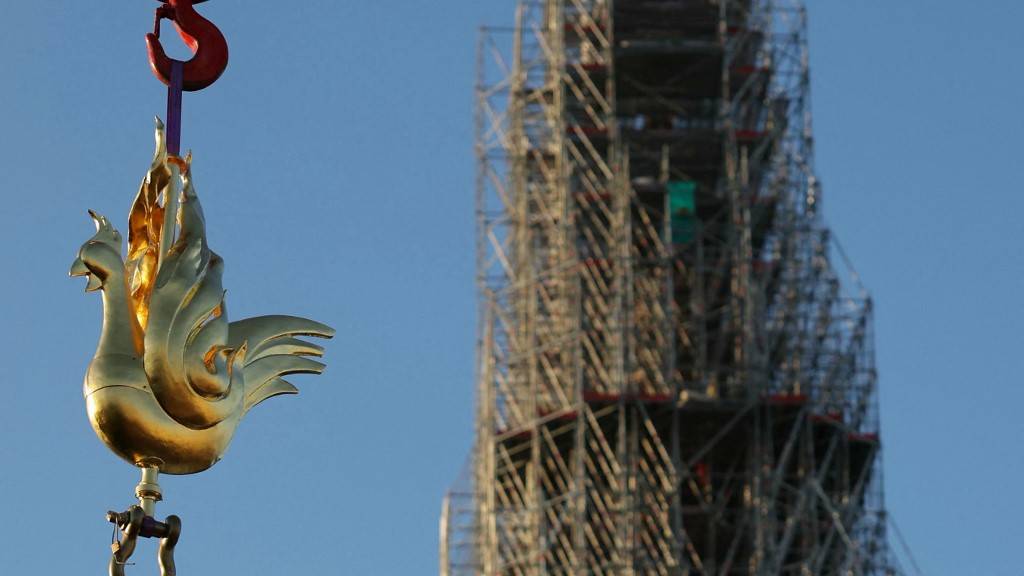 The new golden rooster containing relics is lifted by crane to be installed atop the spire of Notre Dame cathedral as part of its reconstruction in Paris. /Thomas Samson/AFP