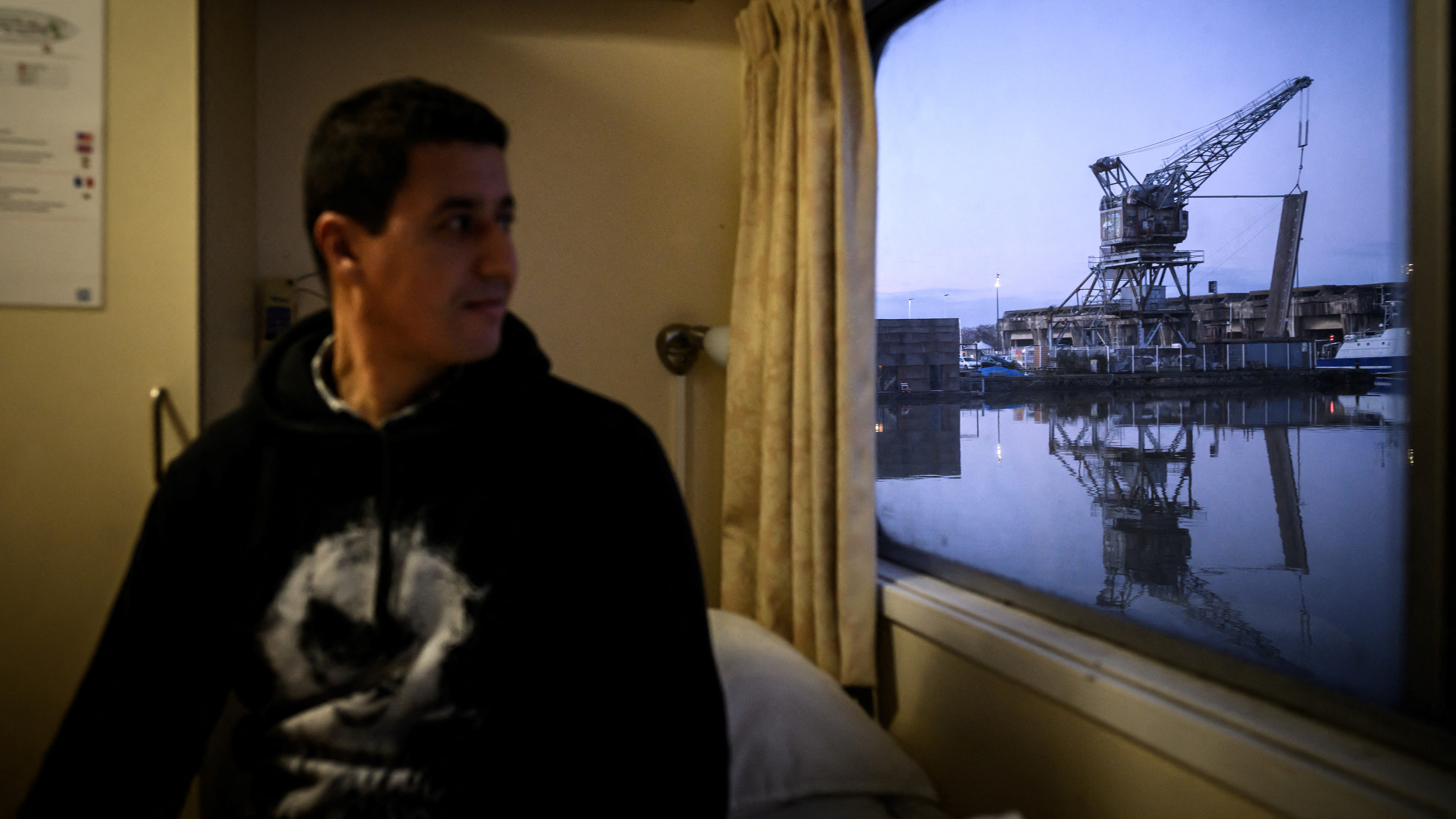 Ismael, a homeless man, sits in his cabin aboard the MS Bordeaux in the south-western French city. /Philippe Lopez/AFP