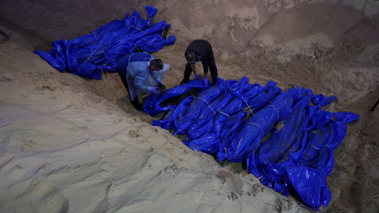 People prepare to bury Palestinians killed by Israeli strikes and fire, after their bodies were released by Israel, at a mass grave in Rafah. /Ibraheem Abu Mustafa/Reuters