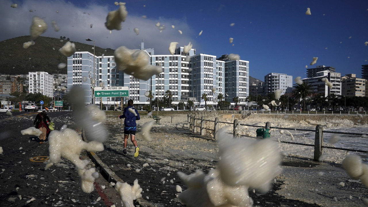 A man runs through sea foam, as a seasonal cold front moved over the Cape Peninsula, following a week of severe weather and flooding in Cape Town, South Africa. /Nic Bothma/Reuters