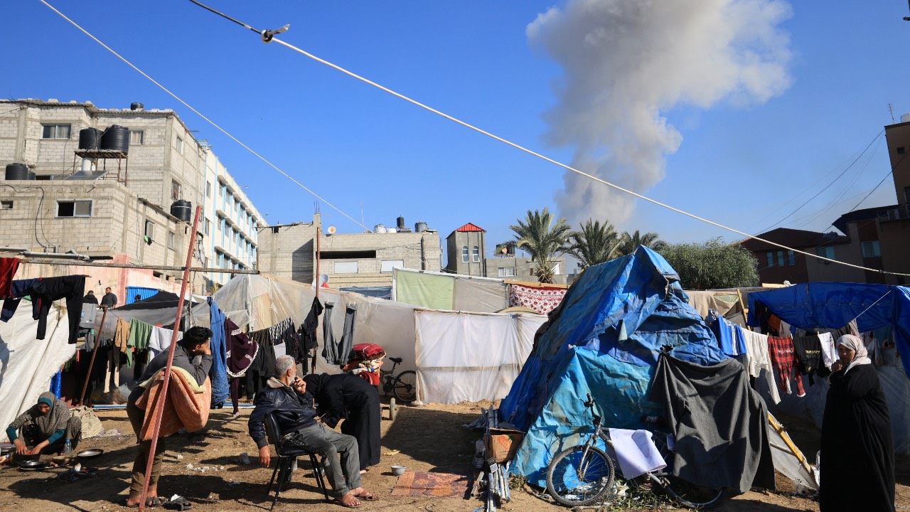 People gather near tents used as temporary shelter, as smoke rises during an Israeli strike on Khan Younis in the southern Gaza Strip. /AFP