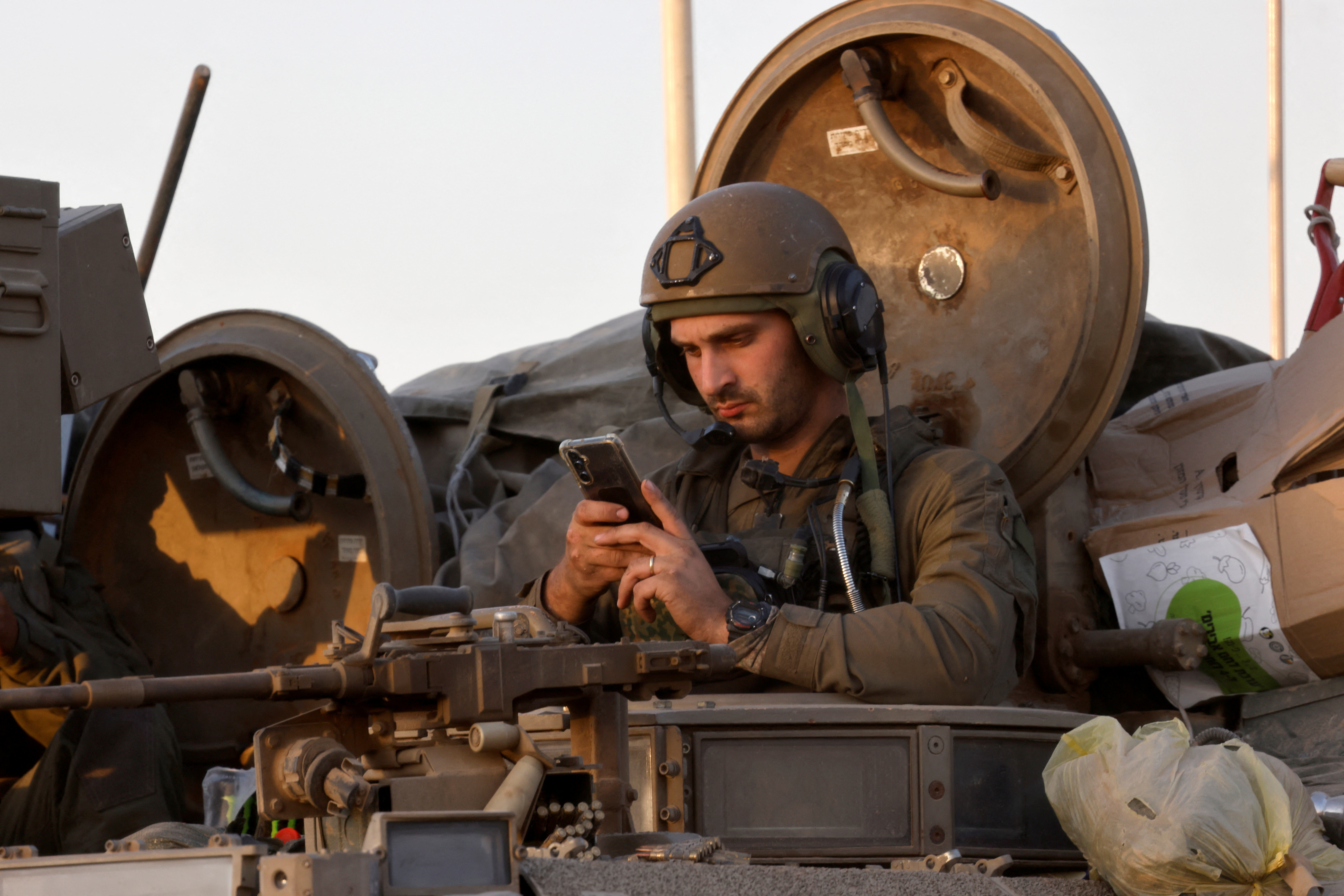 War in 2024: An Israeli soldier scrolls through his smartphone after entering Gaza on a tank. /Amir Cohen/Reuters.
