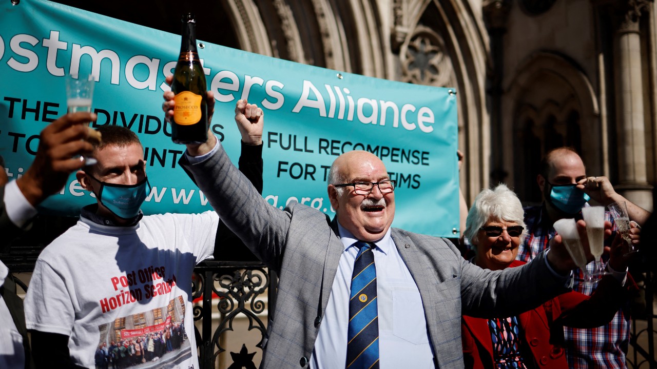 Former subpostmaster Tom Hedges clutches a bottle of champagne outside the Royal Courts of Justice in London, following the ruling. /Tolga Akmen/AFP
